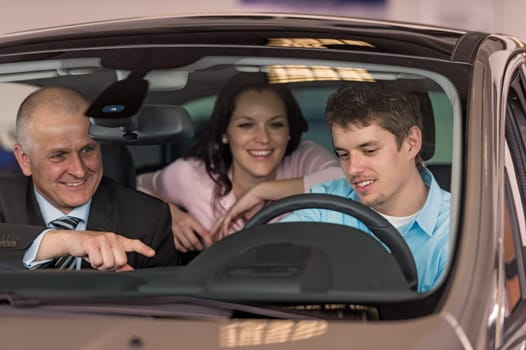 Young couple testing car in dealership