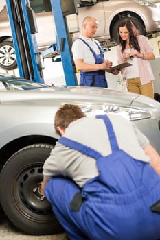 Mechanic showing  paperwork to car owner in garage