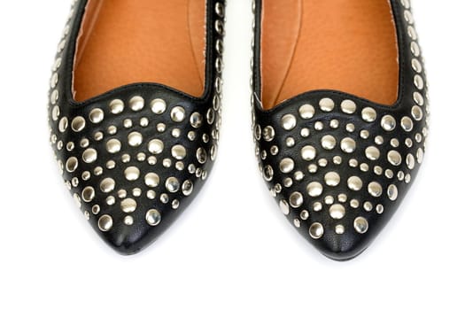 Black women's leather ballet flats with steel rivets close up on a white background