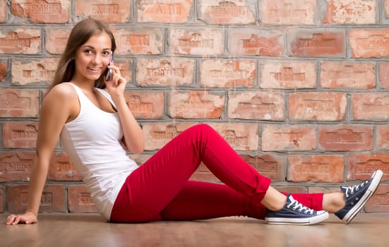 girl casual design with the phone sitting on a brick wall