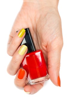 A bottle of red nail polish in a female hand. Isolated on white background