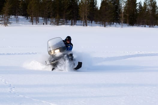 man riding a snowmobile on a background of forest