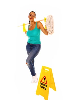 An attractive young woman with brunet hair wearing a blue vest top and yellow rubber cleaning gloves and doing some cleaning on a white background .