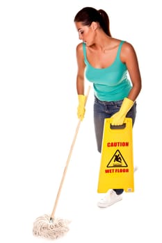 An attractive young woman with brunet hair wearing a blue vest top and yellow rubber cleaning gloves and doing some cleaning on a white background .