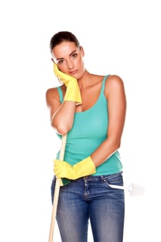 An attractive young woman with brunet hair wearing a blue vest top and yellow rubber cleaning gloves and doing some cleaning on a white background .