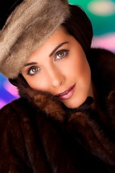 A beautiful woman wearing a warm fur coat on a colorful background.