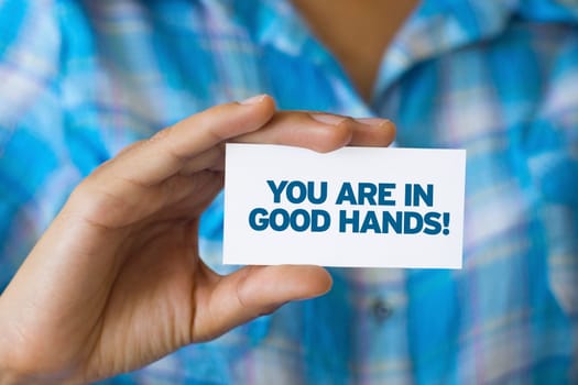 A person holding a white card with the words You are in Good hands