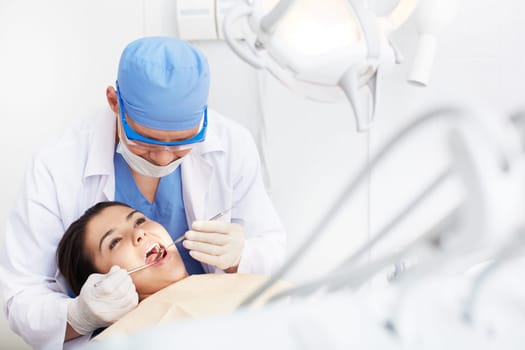 Young girl with open mouth during oral checkup at the dentist’s