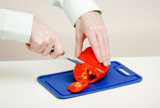 man cuts the a red pepper. Hands close-up