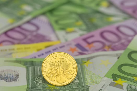 single gold coin on euro banknotes