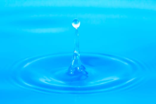 Water droplets drip into blue water