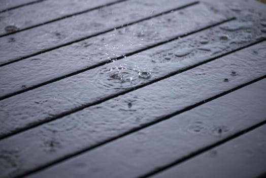 Splashing raindrops on wooden deck close-up