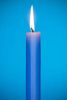 Blue candle burning on the blue background