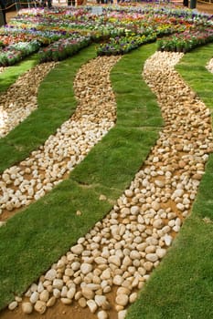 Arrangement of pebbles, grass lawns and flower beds in zigzag curved rows