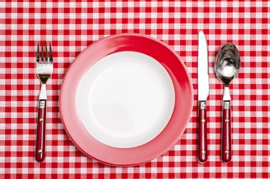 Red place setting in the restaurant on a tablecloth and checked pattern