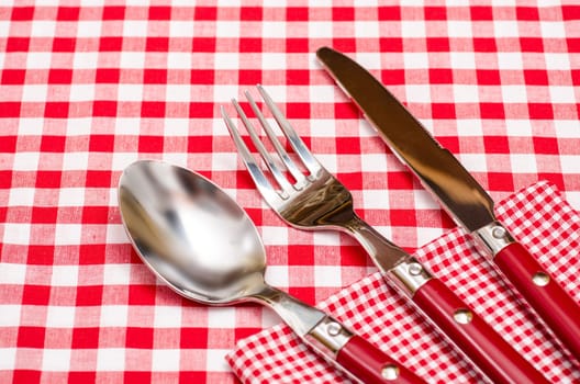 Red cutlery on napkin and tablecloth with checks