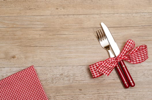 Wooden table with knife and fork and checkered napkin