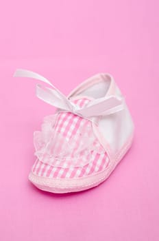 Pink baby shoe with bow in portrait format
