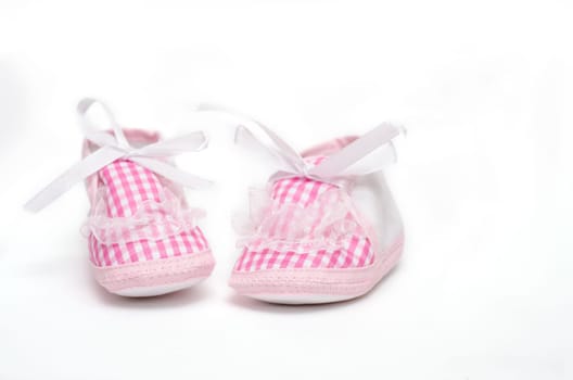 Pair of baby shoes in pink against a white background