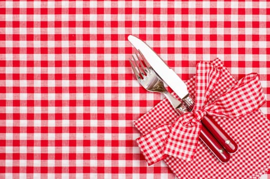 Laid table with cutlery and napkin in red and white with bow