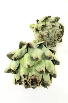 fresh,raw artichokes against a white background