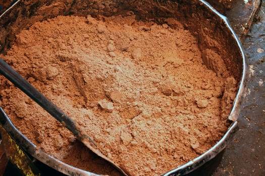 A large metal vat of ground peanuts before adding oil to make peanut butter.