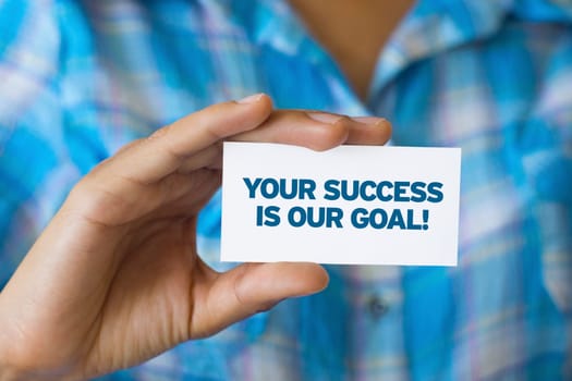 A person holding a white card with the words Your success is our goal