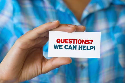 A person holding a white card with the words Questions we can help