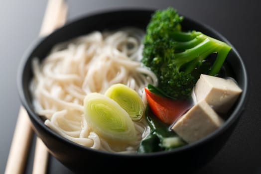 Chinese soup with noodles tofu and vegetables close up