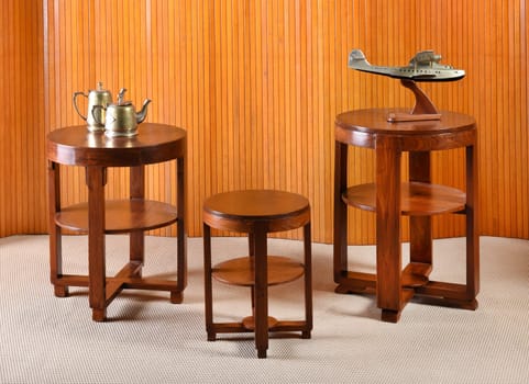Brass tea pots and airplane sculptures on set of three round wooden tables