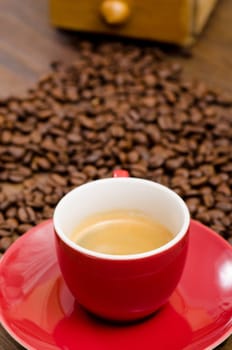 Espresso coffee in red cup in front of brown coffee beans