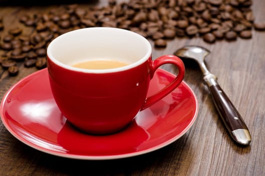 Close-up red cup espresso with spoon and coffee beans