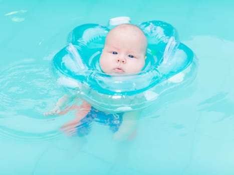 Baby swimming with neck swim ring in pool