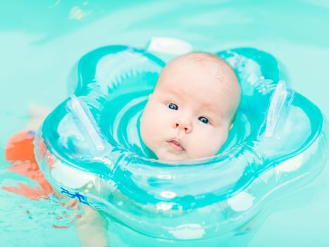 Baby swimming with neck swim ring in pool