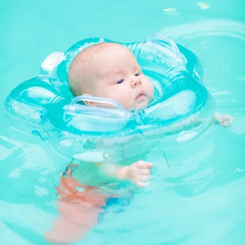 Baby swimming with neck swim ring in pool