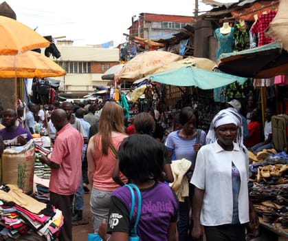 KAMPALA, UGANDA - SEPTEMBER 28, 2012. A white woman walks away through a market shopping among locals in Kampala, Uganda on September 28,2012.