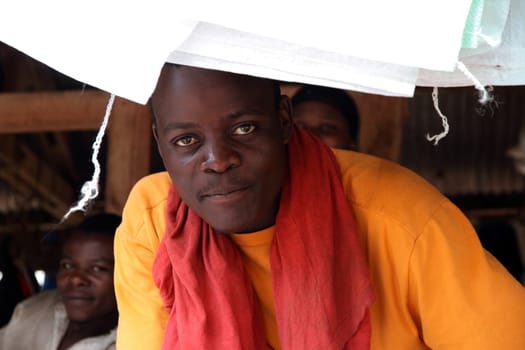 KAMPALA, UGANDA - SEPTEMBER 28, 2012. An attractive young Ugandan market vendor looks into the camera along side his fellow market vendors in Kampala, Uganda on September 28,2012.