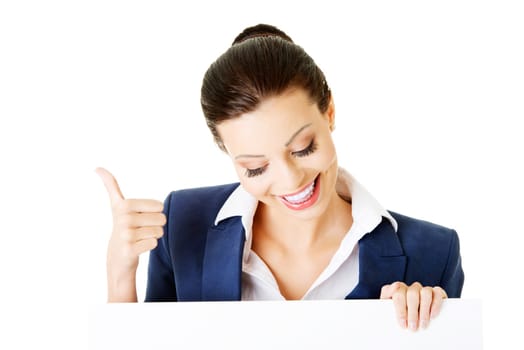 Smiling young business woman showing blank signboard, over white background isolated