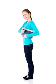 Attractive young student woman with book gesturing OK, isolated on white