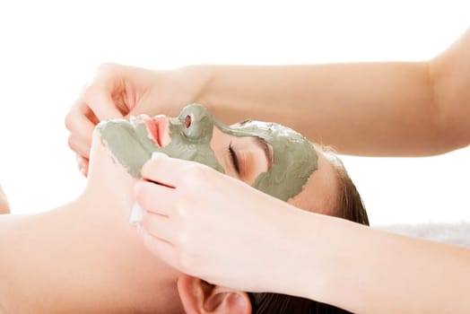 Beauty treatment in spa salon. Woman with facial clay mask. Isolated on white
