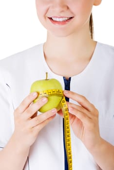 Healthy eating or diet concept. Smiling woman doctor with a green apple and measuring tape.
