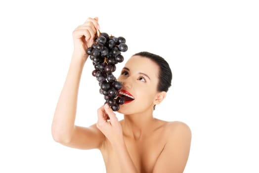 Beautiful sensual brunette eating grapes, isolated on white background