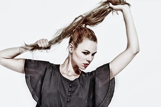 Beautifull young blond woman in the studio holding up her hair