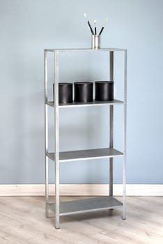 Pens and ornaments on freestanding alumninium bookshelves in modern room