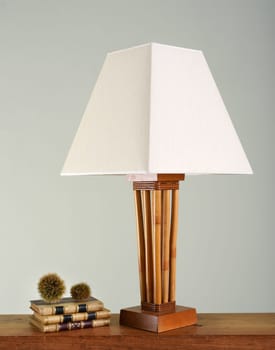 Stack of books next to vintage lamp with white shade