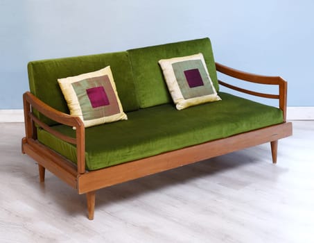 Antique upholstered settee in green with cushions in modern room