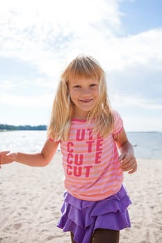 Cute happy young girl having fun at the beach in summer