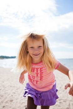 Cute happy young girl having fun at the beach in summer