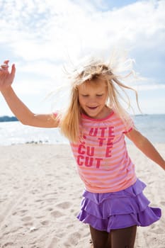 Cute happy young girl having fun at the beach in summer