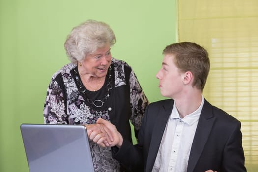 Elderly lady and young man working together on the laptop.